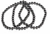 A dark, metallic bracelet made of round beads arranged in a loop on a white background.