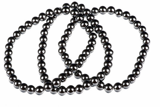 A dark, metallic bracelet made of round beads arranged in a loop on a white background.