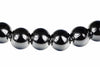 A row of round, dark beads with silver-toned floral inlays on a white background.