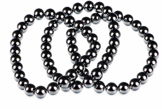 A dark, metallic bracelet made of round beads arranged in a loose coil on a white surface.