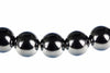 A row of round, dark beads with silver-toned lower halves and small black spacers on a white background.