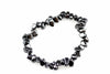 A bracelet made of dark, polished chips arranged in a circle on a white surface.
