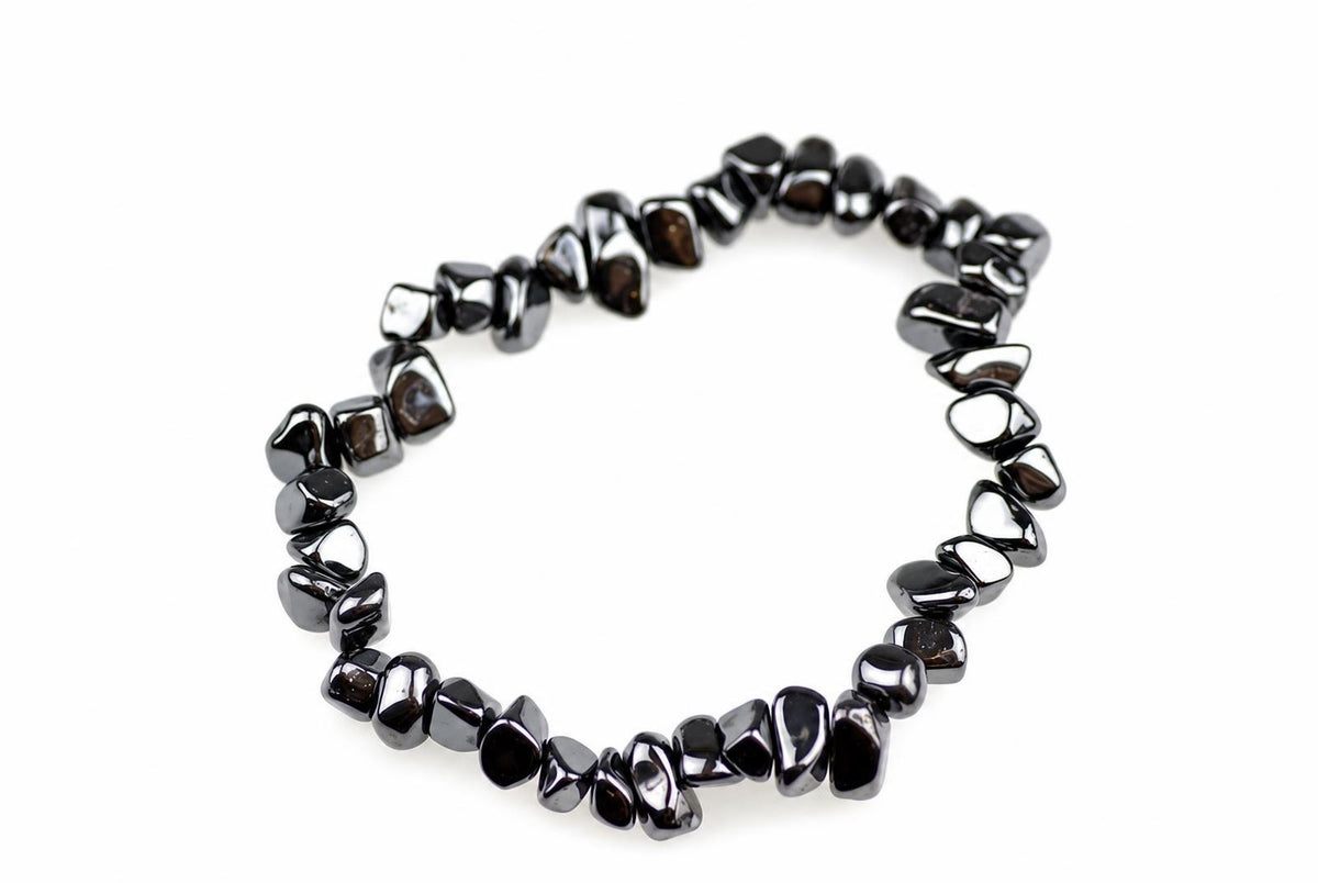 A bracelet made of dark, polished chips arranged in a circle on a white surface.
