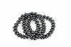 A coiled bracelet made of glossy black spherical beads on a white surface.