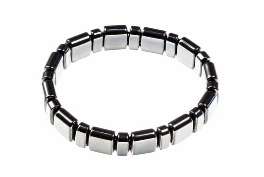 A bracelet made of alternating black and silver-toned square beads arranged in a circle on a white surface.