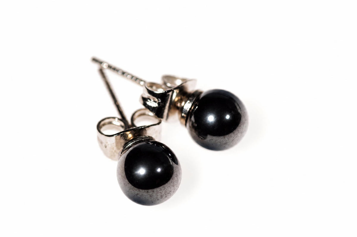 A pair of stud earrings with round, black beads and silver-toned posts on a white surface.