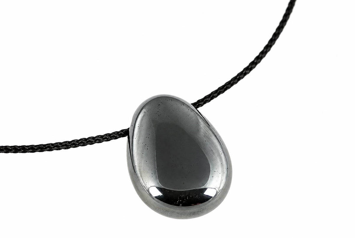 A polished dark grey hematite drop pendant hangs from a black cord, with bright reflections along its rounded lower edge.