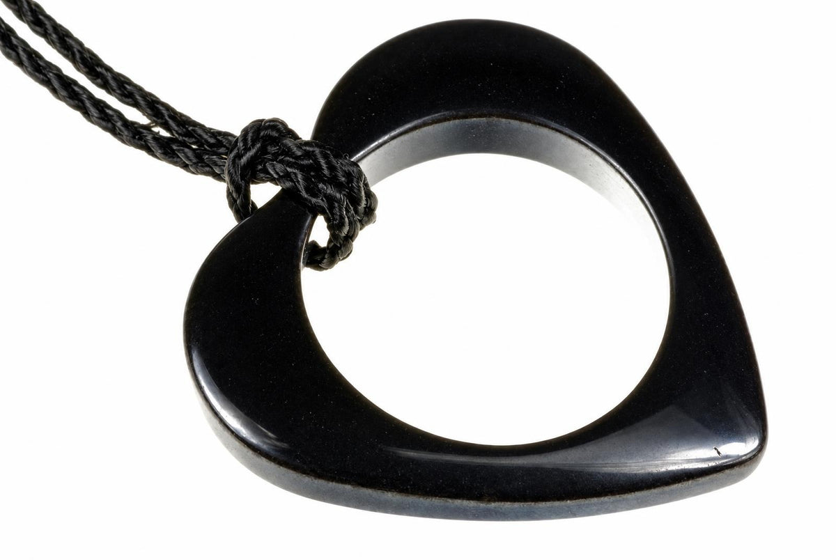 A black heart-shaped pendant with a central hole, attached to a braided black cord against a white background.