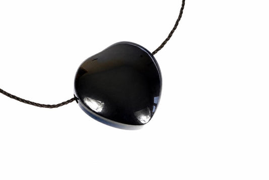 A glossy black heart-shaped pendant on a dark cord, set against a plain white background.