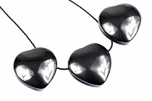 A necklace with three dark, heart-shaped pendants on a black cord against a white background.