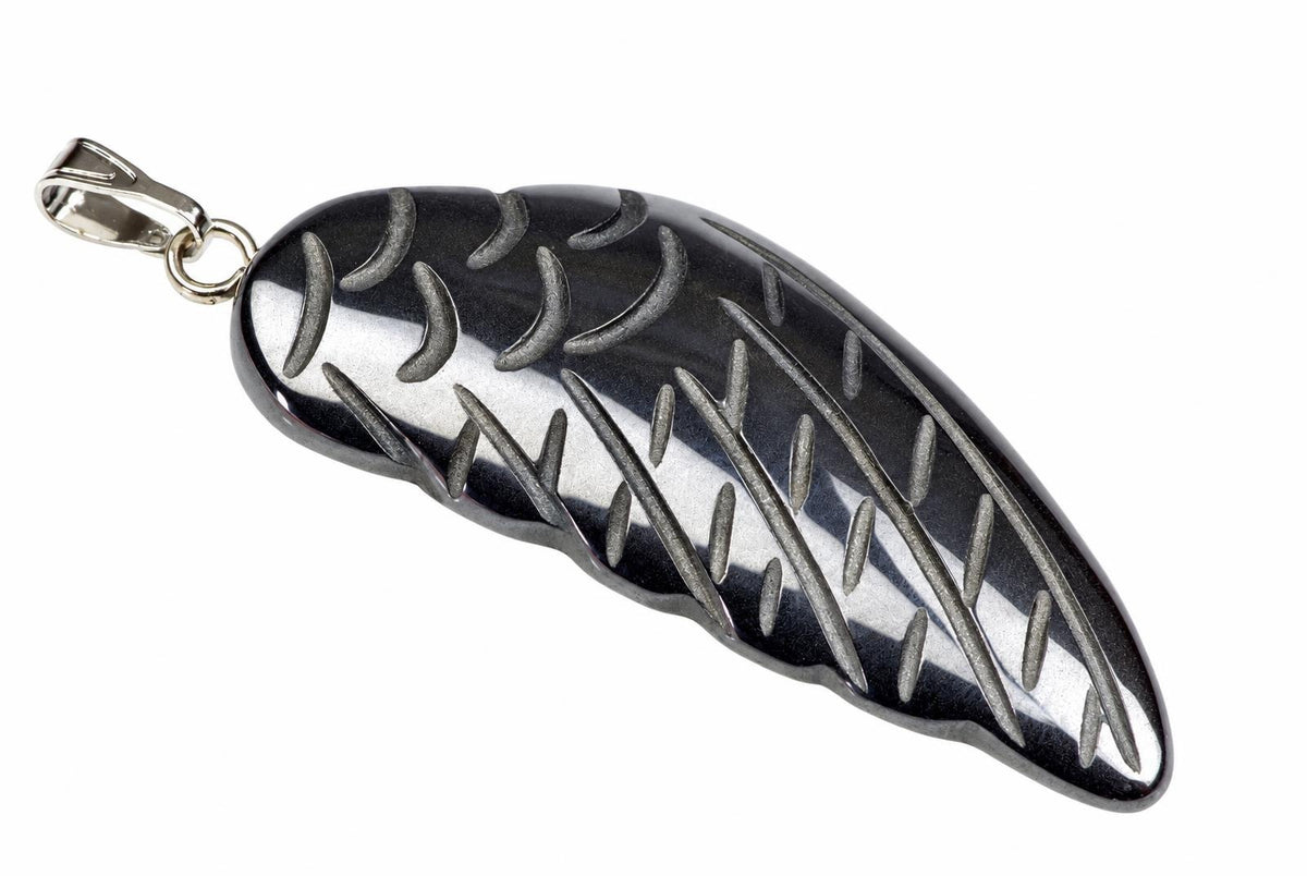 A silver-toned pendant shaped like a wing, featuring engraved lines and crescents on a dark surface against a white background.