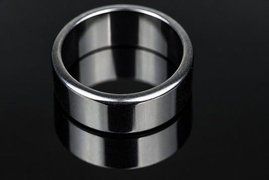 A silver-toned ring with a smooth, flat band sits on a dark surface.