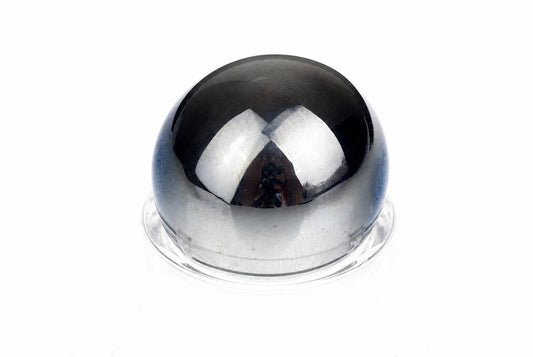 A polished, dark grey sphere sits on a clear base against a white background.
