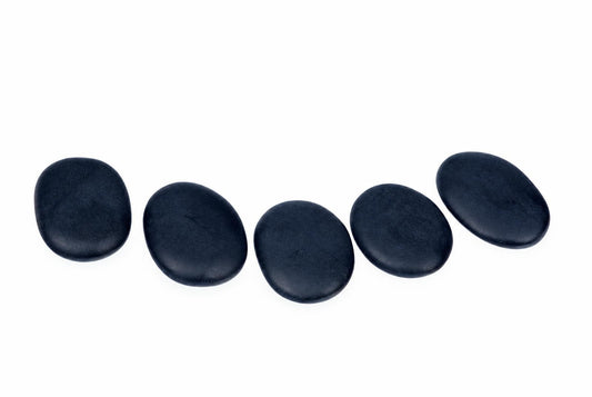 Five smooth, dark oval stones arranged in a gentle curve on a white surface.
