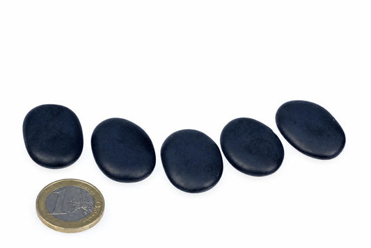 Five smooth, dark oval stones arranged on a white surface with a one-euro coin for scale.