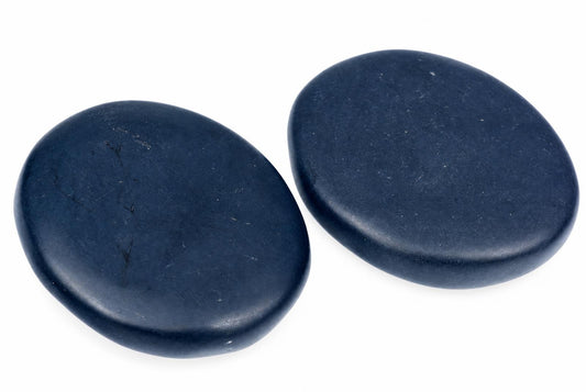 Two smooth, dark blue oval massage stones on a white surface.