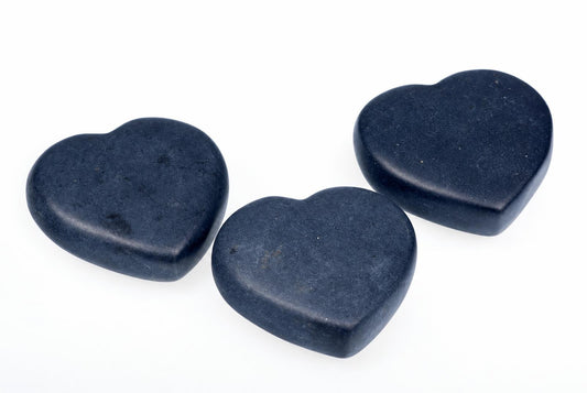 Three dark blue, heart-shaped massage stones arranged on a white surface.