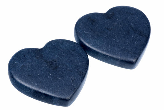 Two dark blue, heart-shaped massage stones on a white background.