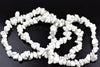 A white and grey speckled Howlite chip bracelet coiled on a dark surface.