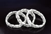 Two white and grey veined triangle-shaped bracelets lie on a dark surface.
