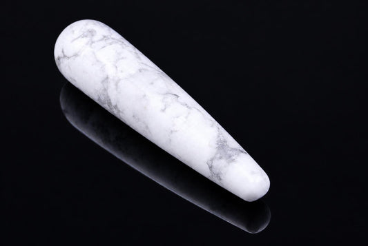 A white and grey veined massage stick with rounded ends rests on a dark, reflective surface.
