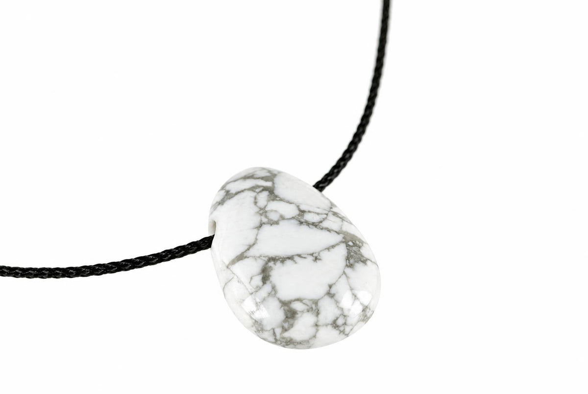 A white pendant with grey veining hangs from a black cord against a plain background.
