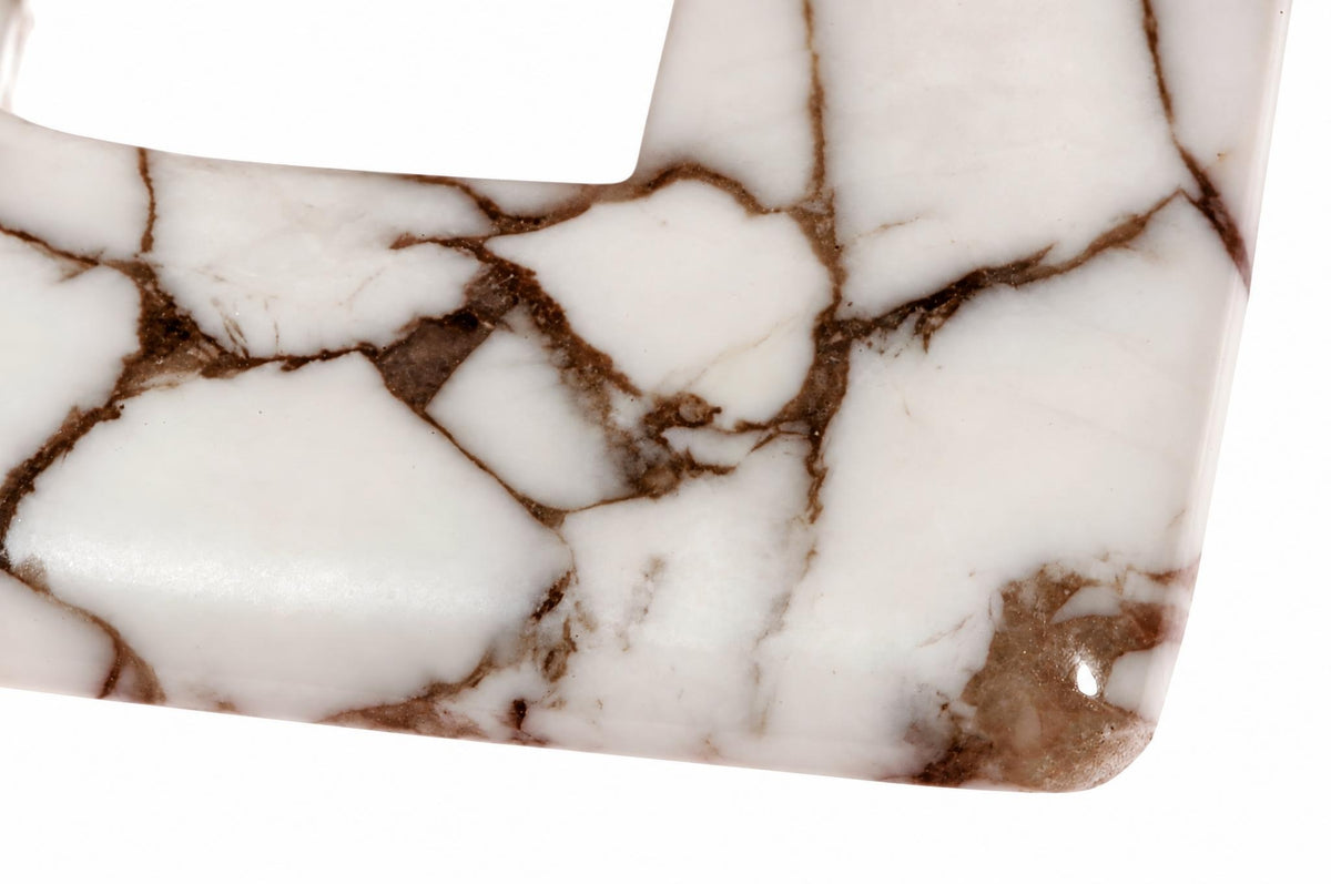 A close-up of a white pendant with brown veining, set against a plain background.