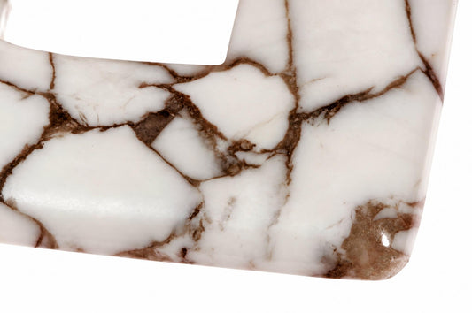 A close-up of a white pendant with brown veining, set against a plain background.