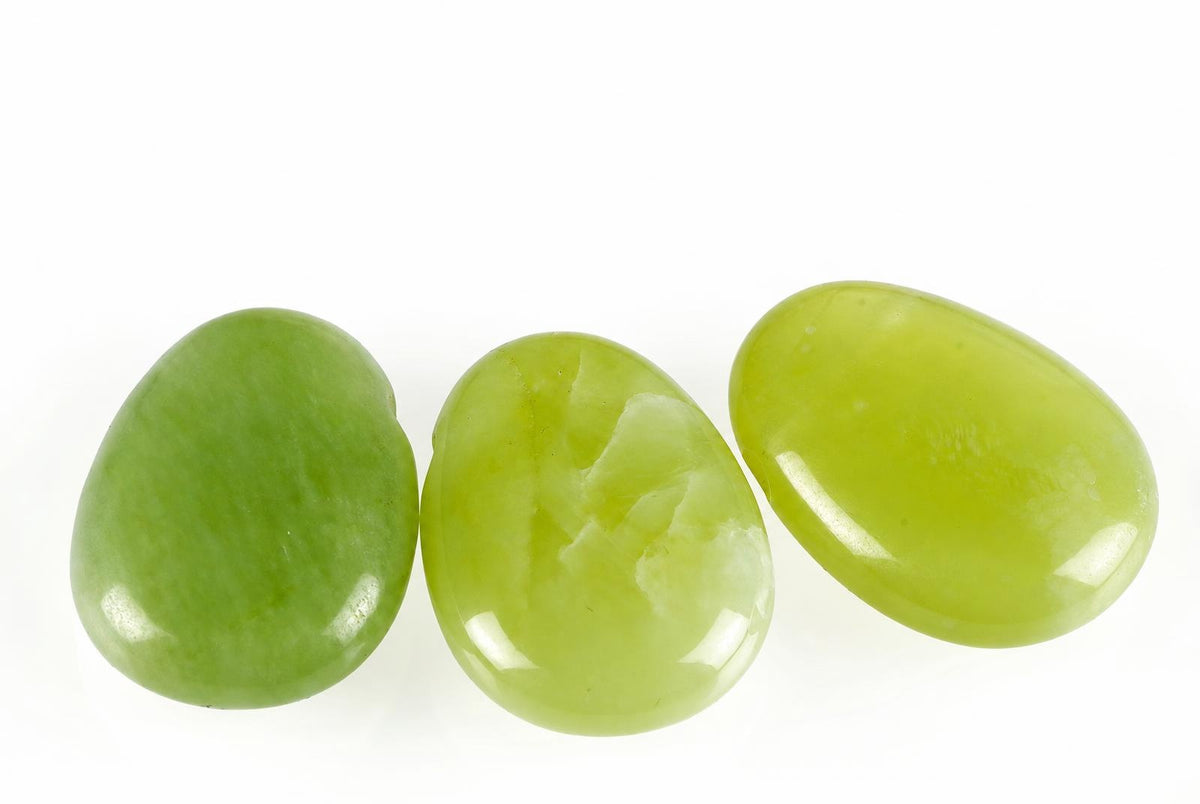 Three smooth, polished green stones in oval shapes arranged on a white surface.