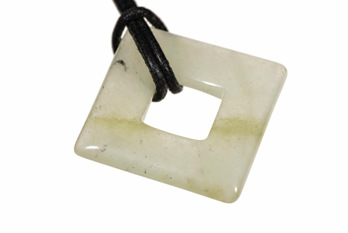 A square jade pendant with a central hole, pale green and white tones, on a black cord against a white background.