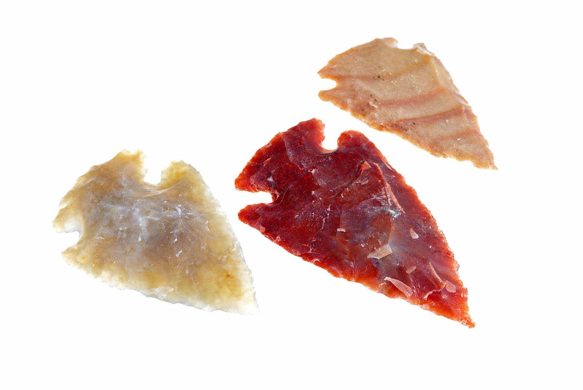 Three jasper arrowheads in pale yellow, deep red and light brown on a white background.