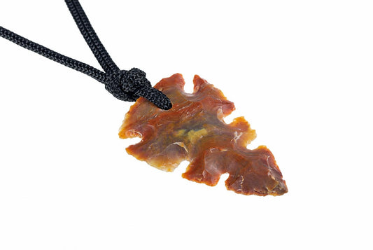 A jasper pendant shaped like an arrowhead, with brown and yellow tones, hangs from a black cord against a white background.