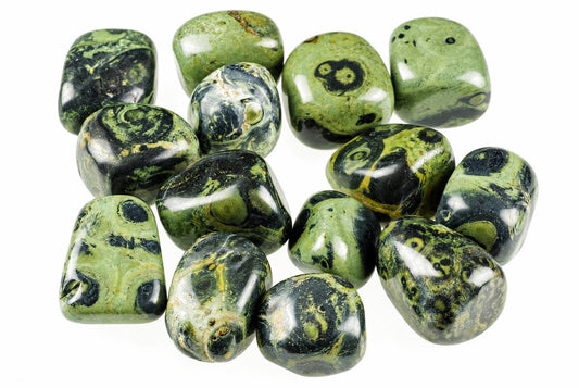 Twelve polished Kambaba jasper tumbled stones with green, black and yellow swirls on a white background.
