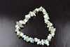 A Larimar bracelet made of irregular chips in pale blue, white and brown tones on a dark surface.