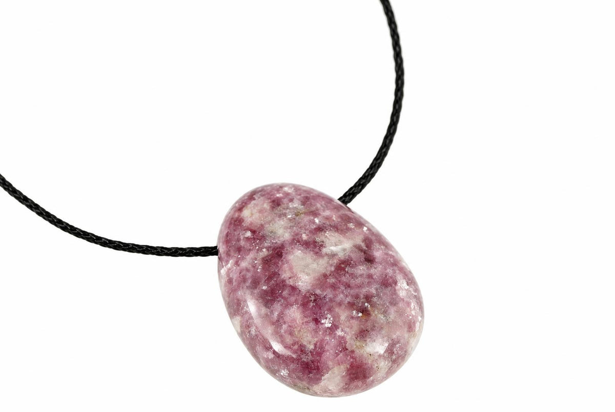 A polished oval pendant with pink and white speckled stone on a black cord against a white background.