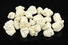 A pile of white, irregular magnesite crystals on a dark surface.