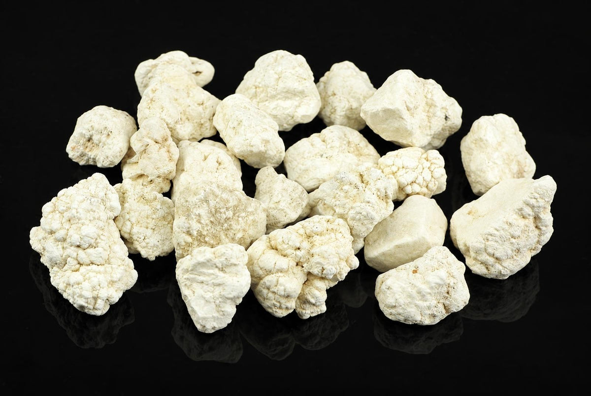 A pile of white, irregular magnesite crystals on a dark surface.