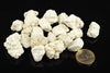 A pile of white, irregular magnesite stones on a dark surface next to a one euro coin.