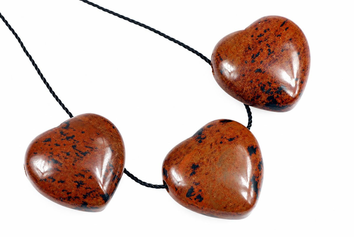 A necklace with three polished, heart-shaped brown stones featuring black speckles on a white background.