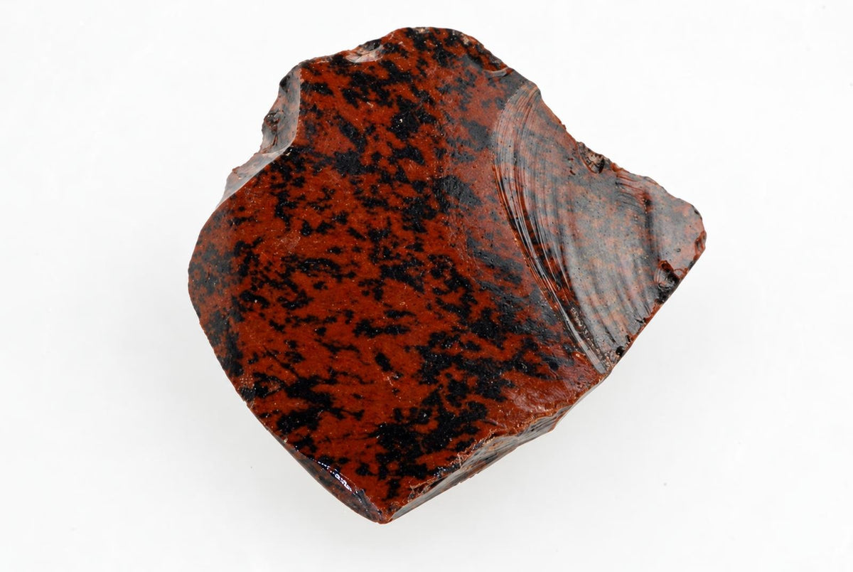 A polished, irregular piece of mahogany obsidian with a dark red base and black speckles on a white surface.