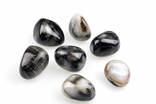Seven polished stones with black, white and grey patterns on a pale surface.