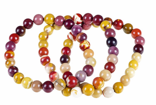 A bracelet of round beads in red, yellow, purple and cream colours arranged on a white surface.