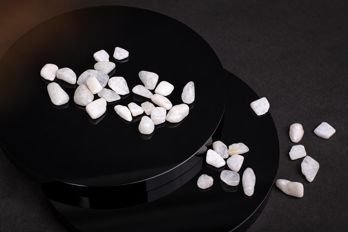 White, smooth stones on a black circular surface with some scattered nearby.