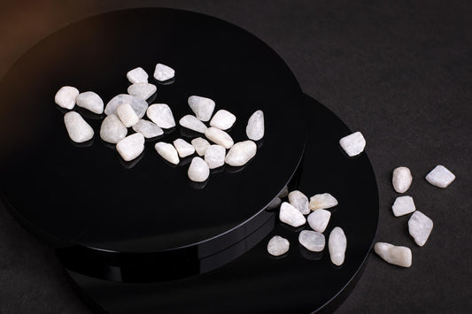 White, smooth stones on a black circular surface with some scattered nearby.
