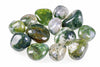 A collection of polished moss agate stones with green and white patterns on a pale surface.