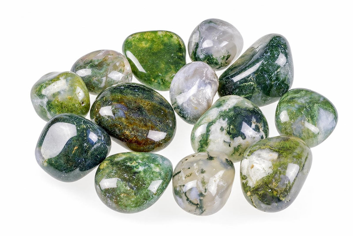 A collection of polished moss agate stones with green and white patterns on a pale surface.