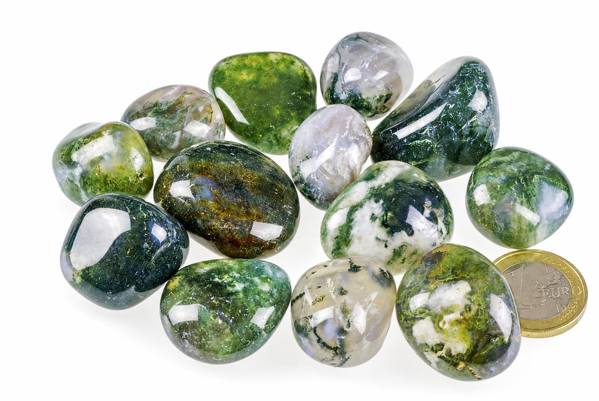 A collection of polished moss agate stones with green and white patterns, arranged on a pale surface next to a one-euro coin.