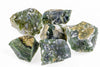 Six rough moss agate stones with green, white and brown patches on a pale surface.