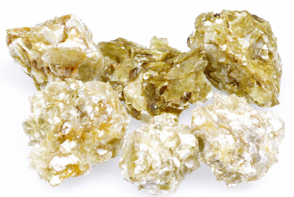 Six rough, translucent crystals of muscovite with pale yellow and white tones on a plain white surface.