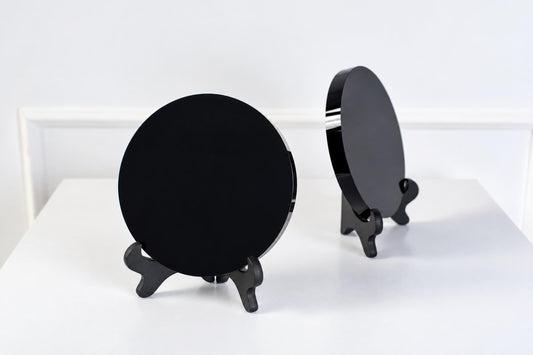 Two black circular mirrors on stands, one facing forward and the other angled, set against a white background.